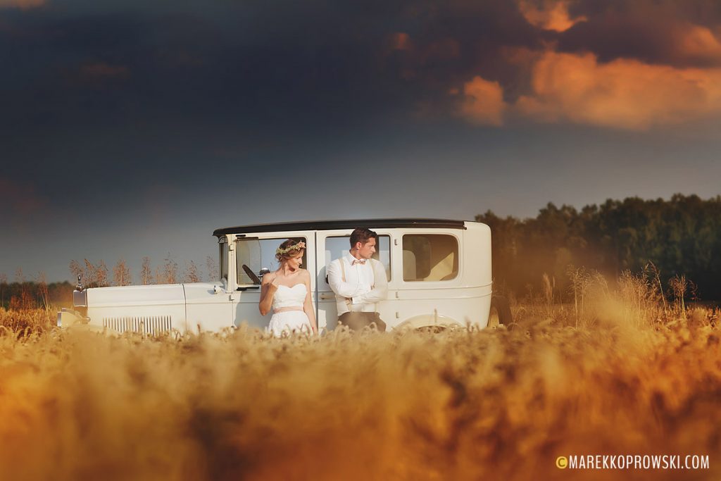 Para młoda oparta o samochód weselny podczas romantycznej sesji ślubnej